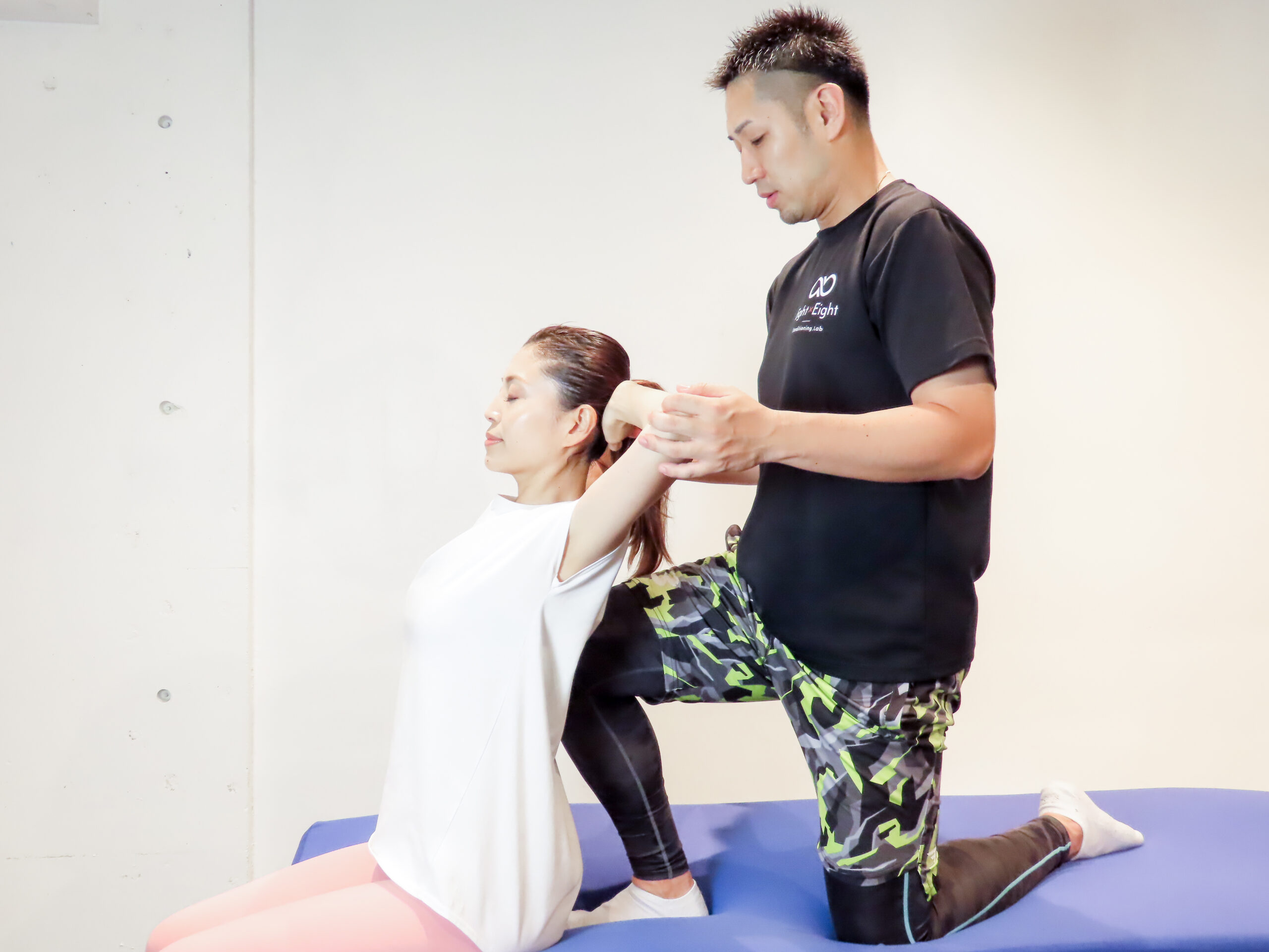 トレーナーのサポートで上半身をストレッチする様子